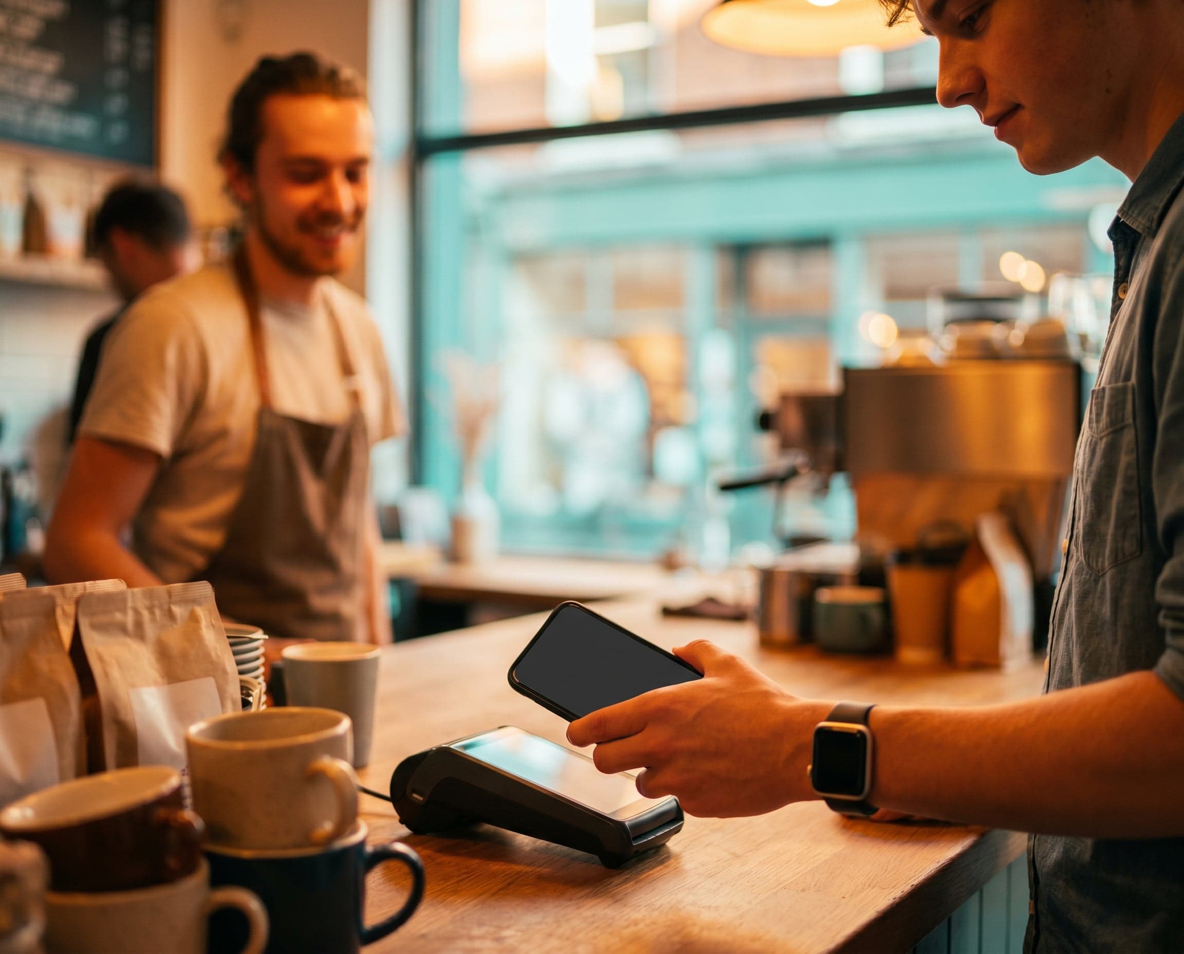 A customer taps a phone to pay on a card reader