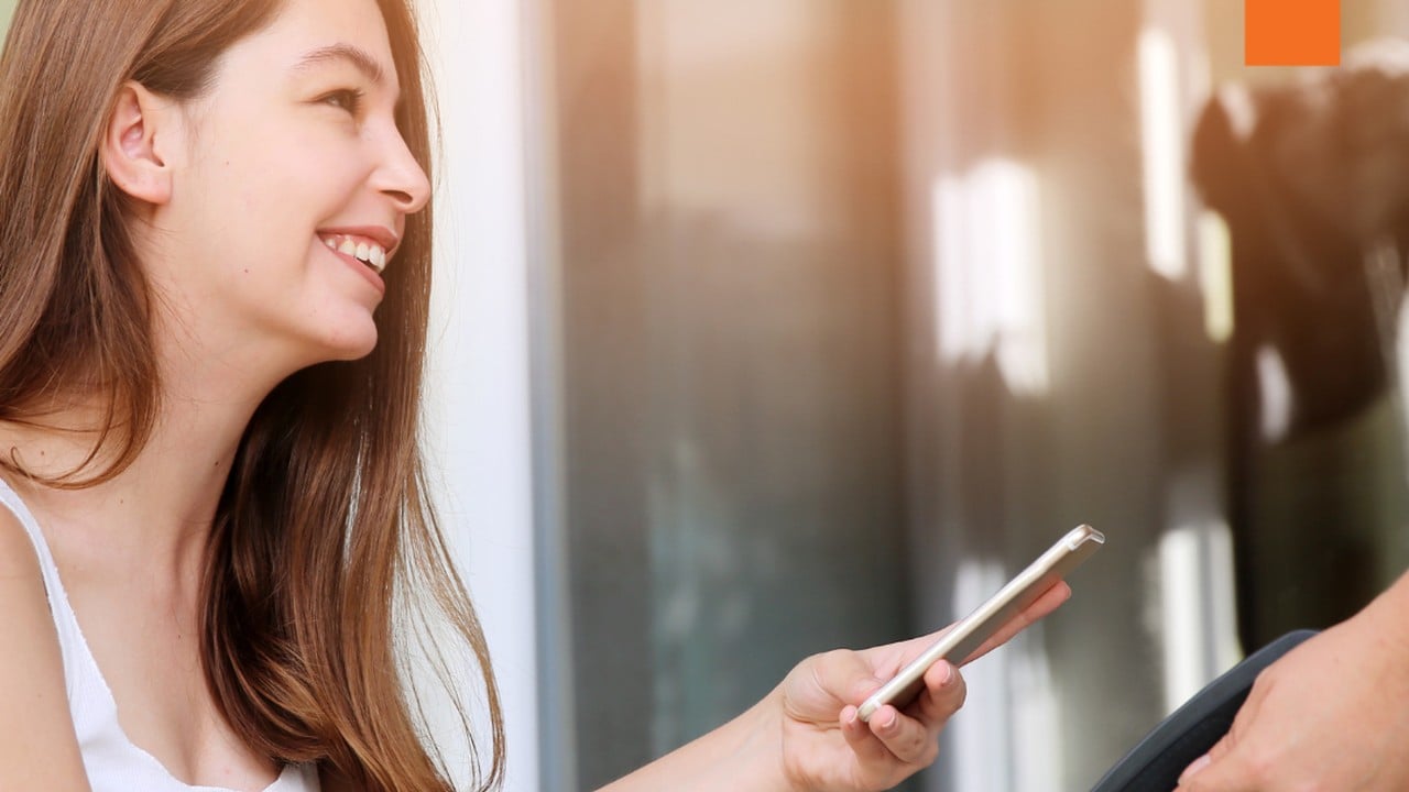 A customer smiling as she pays with her phone at a contactless reader